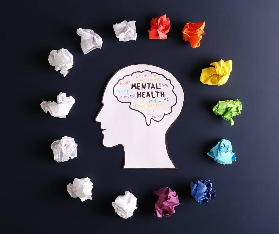 bela glava na modrem ozadju, v glavi napis duševno zdravje, okoli glave so raznobarvni papirčki